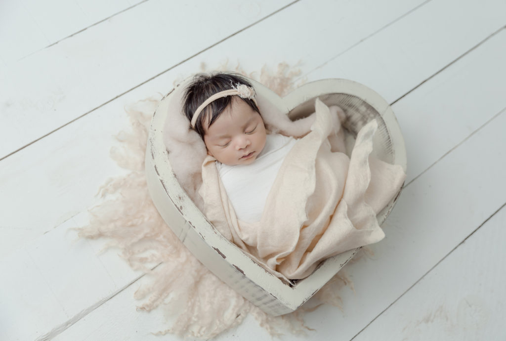 newborn baby girl photo in heart shape bowl with fluffy wool