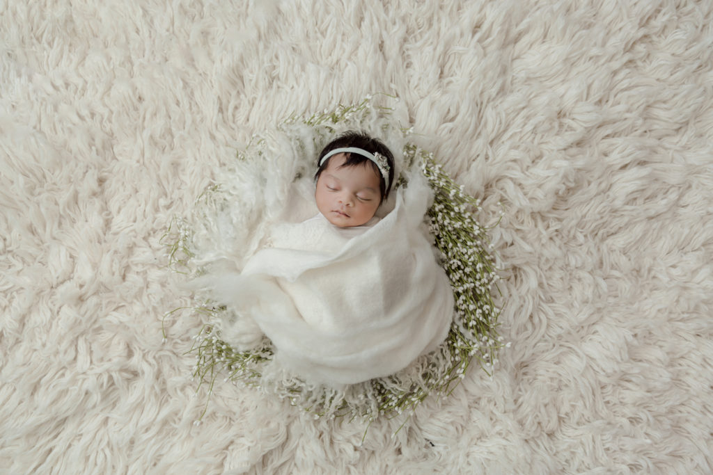 sweet baby girl wrapped in a white wreath newborn photo