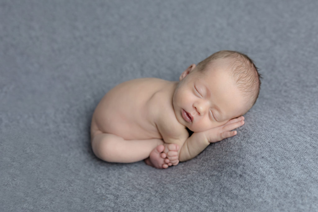 Baby posed on a blanket with 10 toes sticking out womb pose