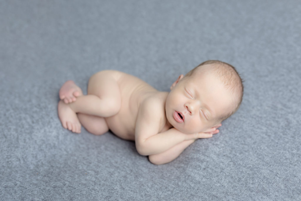 baby lying on hands with feet crossed in a photo session