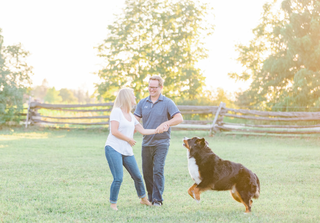 couple playing with dog during an engagement session in Carp