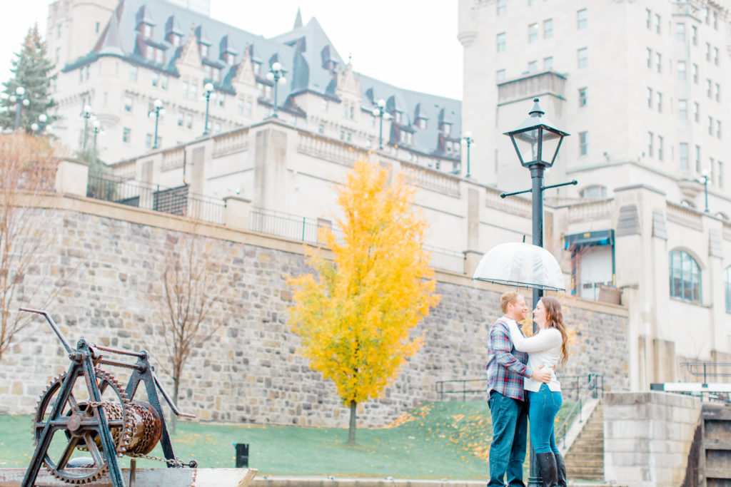 fall Engagement Session Downtown Ottawa during Sunset National Art Gallery grey loft studio ottawa wedding photographer videographer engagement kanata orleans nepean beautiful locations for engagement photos in ottawa chateau laurier majors hill park pop champagne pink and black dress rainy day engagement session using clear umbrella