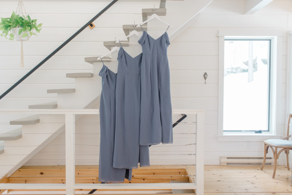 unique spot for hanging the bridesmaid dresses with white hangers - Matching white hangers - bridesmaids in blue robes - holding bouquets in water - sitting on a bed - quebec wedding photographer Wakefield bridgeottawa wedding photographer couple getting married in winter le belvedere wedding sunset grey loft studio couples in love affordable kanata photographer cheap wedding fun wedding romantic wedding bridesmaids