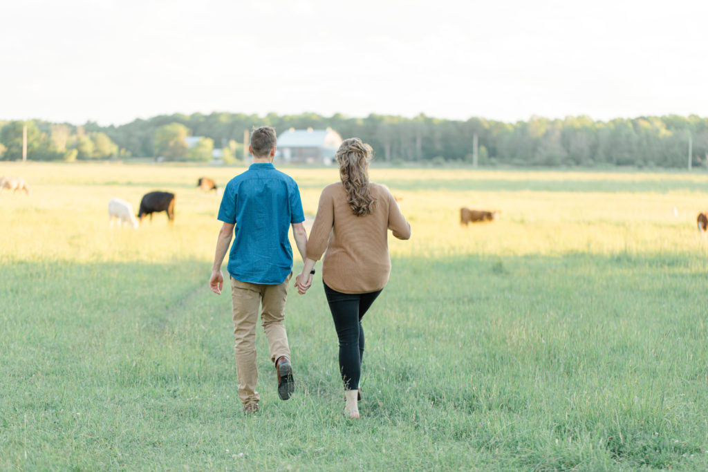Cows during Engagement Session - Poses during Engagement Session  Sunset - Natural Posing for Photo Session - Couples Photo Session Fun - Fun on the Farm - Farm Engagement Session - Blue and Brown Engagement Session Inspiration - Natural Engagement Session Posing - Ideas for what to wear for Engagement Photography, Modern Engagement Session Inspiration Wardrobe Ideas. Unsure of what to wear for your engagement photos, we've got you! Romantic brown with black leggings for Summer Engagement in Almonte. Grey Loft Studio is Ottawa's Wedding and Engagement Photographer for Real couples, showcasing photos that are modern, bright, and fun.