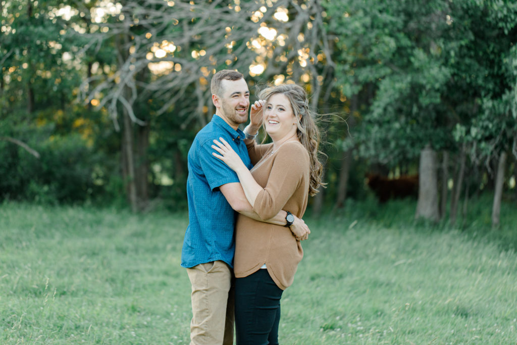 Cow Photobomb - Cows during Engagement Session - Poses during Engagement Session  Sunset - Natural Posing for Photo Session - Couples Photo Session Fun - Fun on the Farm - Farm Engagement Session - Blue and Brown Engagement Session Inspiration - Natural Engagement Session Posing - Ideas for what to wear for Engagement Photography, Modern Engagement Session Inspiration Wardrobe Ideas. Unsure of what to wear for your engagement photos, we've got you! Romantic brown with black leggings for Summer Engagement in Almonte. Grey Loft Studio is Ottawa's Wedding and Engagement Photographer for Real couples, showcasing photos that are modern, bright, and fun.