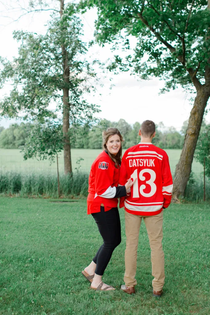 Ottawa Sens Jersey - Detroit Redwings Jersey - Datsyuk- Engagement Session Inspiration. - Poses during Engagement Session  Sunset - Natural Posing for Photo Session - Couples Photo Session Fun - Fun on the Farm - Farm Engagement Session - Blue and Brown Engagement Session Inspiration - Natural Engagement Session Posing - Ideas for what to wear for Engagement Photography, Modern Engagement Session Inspiration Wardrobe Ideas. Unsure of what to wear for your engagement photos, we've got you! Romantic brown with black leggings for Summer Engagement in Almonte. Grey Loft Studio is Ottawa's Wedding and Engagement Photographer for Real couples, showcasing photos that are modern, bright, and fun.