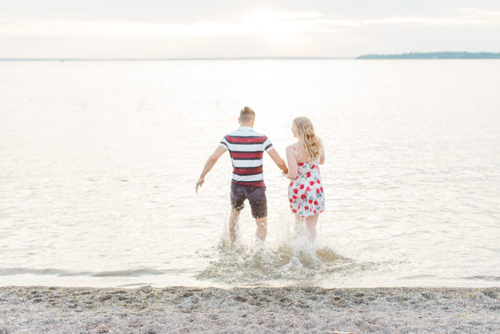 Cute Poses on the beach - Ideas for what to wear for Engagement Photography, Modern Engagement Session Inspiration Wardrobe Ideas. Unsure of what to wear for your engagement photos, we've got you! Romantic floral dress. Navy, Burgundy, & White T-shirt Polo & Navy shorts . Boat Shoes and Fancy. beaded sandals. Engagement at Britannia Beach, Nepean. Grey Loft Studio is Ottawa's Wedding and Engagement Photographer Videographer for Real couples, showcasing photos that are modern, bright, and fun.