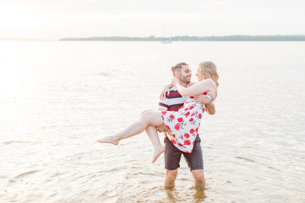 Cute Poses on the beach in Water - Ideas for what to wear for Engagement Photography, Modern Engagement Session Inspiration Wardrobe Ideas. Unsure of what to wear for your engagement photos, we've got you! Romantic floral dress. Navy, Burgundy, & White T-shirt Polo & Navy shorts . Boat Shoes and Fancy. beaded sandals. Engagement at Britannia Beach, Nepean. Grey Loft Studio is Ottawa's Wedding and Engagement Photographer Videographer for Real couples, showcasing photos that are modern, bright, and fun.