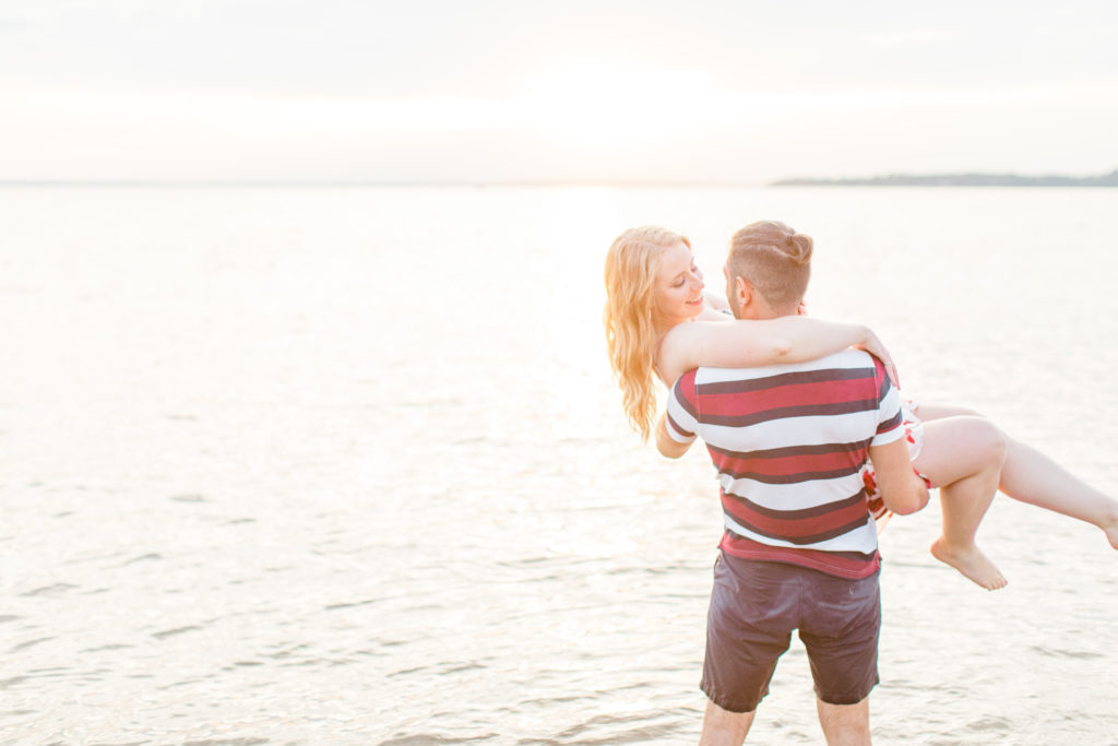 Cute Poses on the beach in Water - Ideas for what to wear for Engagement Photography, Modern Engagement Session Inspiration Wardrobe Ideas. Unsure of what to wear for your engagement photos, we've got you! Romantic floral dress. Navy, Burgundy, & White T-shirt Polo & Navy shorts . Boat Shoes and Fancy. beaded sandals. Engagement at Britannia Beach, Nepean. Grey Loft Studio is Ottawa's Wedding and Engagement Photographer Videographer for Real couples, showcasing photos that are modern, bright, and fun.