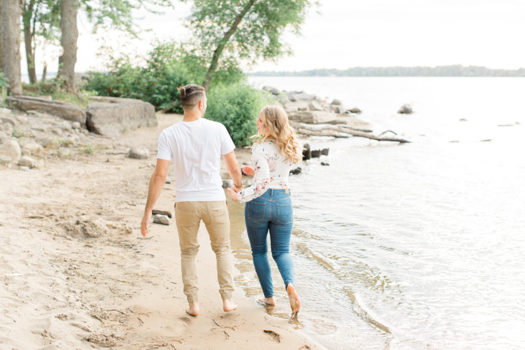 Walking on the Beach - Ideas for what to wear for Engagement Photography, Modern Engagement Session Inspiration Wardrobe Ideas. Unsure of what to wear for your engagement photos, we've got you! Romantic floral shirt & jeans.  White T-shirt & neutral pants . Boat Shoes and Fancy. beaded sandals. Engagement at Petrie Island, Orleans. Grey Loft Studio is Ottawa's Wedding and Engagement Photographer Videographer for Real couples, showcasing photos that are modern, bright, and fun.