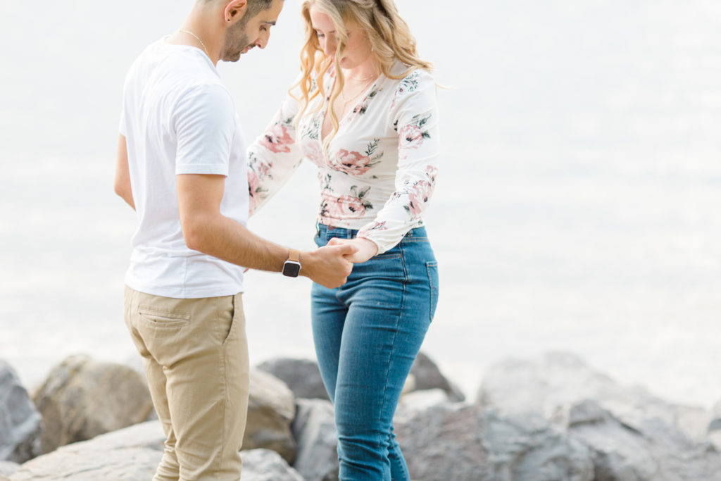 Holding Hands on the beach - Ideas for what to wear for Engagement Photography, Modern Engagement Session Inspiration Wardrobe Ideas. Unsure of what to wear for your engagement photos, we've got you! Romantic floral shirt & jeans.  White T-shirt & neutral pants . Boat Shoes and Fancy. beaded sandals. Engagement at Petrie Island, Orleans. Grey Loft Studio is Ottawa's Wedding and Engagement Photographer Videographer for Real couples, showcasing photos that are modern, bright, and fun.