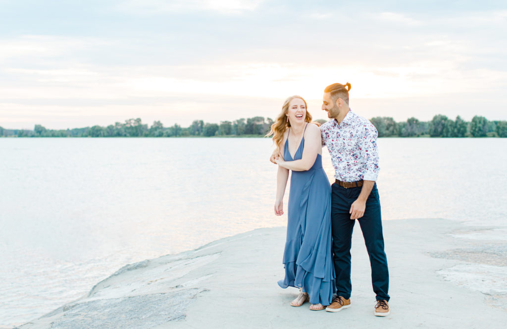 Cute Poses on the beach - Ideas for what to wear for Engagement Photography, Modern Engagement Session Inspiration Wardrobe Ideas. Unsure of what to wear for your engagement photos, we've got you! Romantic floral shirt & jeans.  White T-shirt & neutral pants . Boat Shoes and Fancy. beaded sandals. Engagement at Petrie Island, Orleans. Grey Loft Studio is Ottawa's Wedding and Engagement Photographer Videographer for Real couples, showcasing photos that are modern, bright, and fun.