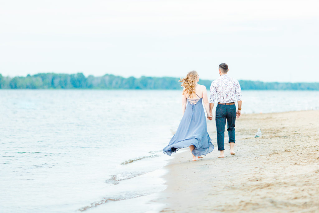 Cute Poses on the beach - Ideas for what to wear for Engagement Photography, Modern Engagement Session Inspiration Wardrobe Ideas. Unsure of what to wear for your engagement photos, we've got you! Romantic floral shirt & jeans.  White T-shirt & neutral pants . Boat Shoes and Fancy. beaded sandals. Engagement at Petrie Island, Orleans. Grey Loft Studio is Ottawa's Wedding and Engagement Photographer Videographer for Real couples, showcasing photos that are modern, bright, and fun.