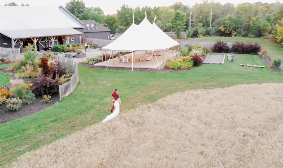 Arial Shot - Bride and Groom Posing in Field of Wheat - Ruby, Off-White, Silver, Greenery. Eucalyptus Leaves. An inspiration filled with soft neutrals, lush florals, and layers of romantic textures all set at Evermore Weddings and Events, Almonte Ontario. 
Grey Loft Studio shot with Canon 5D Mark 4. Ottawa Wedding Photographer & Videographer Team.