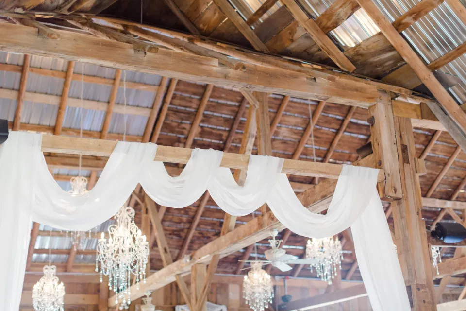 Hanging White Drapery in Evermore. Indoor Heritage Barn at Evermore Wedding's and Events - Almonte - Hanging Chandeliers, Rustic Modern Chairs, White linens. Ruby Red Lovely Wedding at Evermore. 