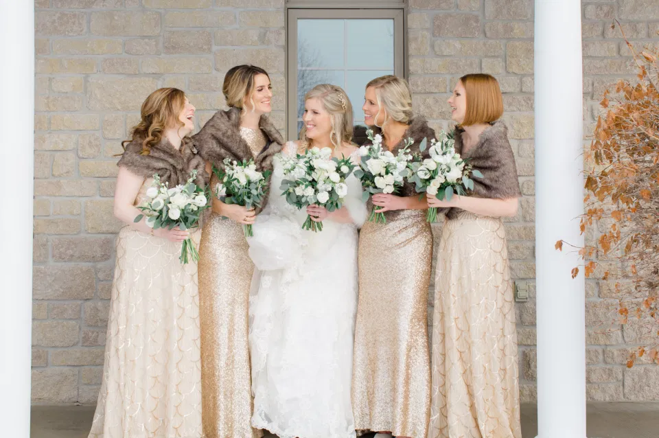 Bride with Bridesmaids about to get into the Limo - White, Greenery, Gold Inspired with brown furs - Winter Wedding - Bride with Bridesmaids - Gold, White, Greenery with Brown Furs -  NYE Wedding - Natural Wedding Posing - Ideas for what to wear for Wedding on NYE Photography, Modern Wedding NYE Wardrobe inspiration- Unsure of what to wear for your wedding, we've got you! Romantic white with greenery theme. Lace Wedding Dress in Ottawa. Grey Loft Studio is Ottawa's Wedding and Engagement Photographer & Videographer for Real couples, showcasing photos that are modern, bright, and fun.  Brookstreet Hotel Kanata 