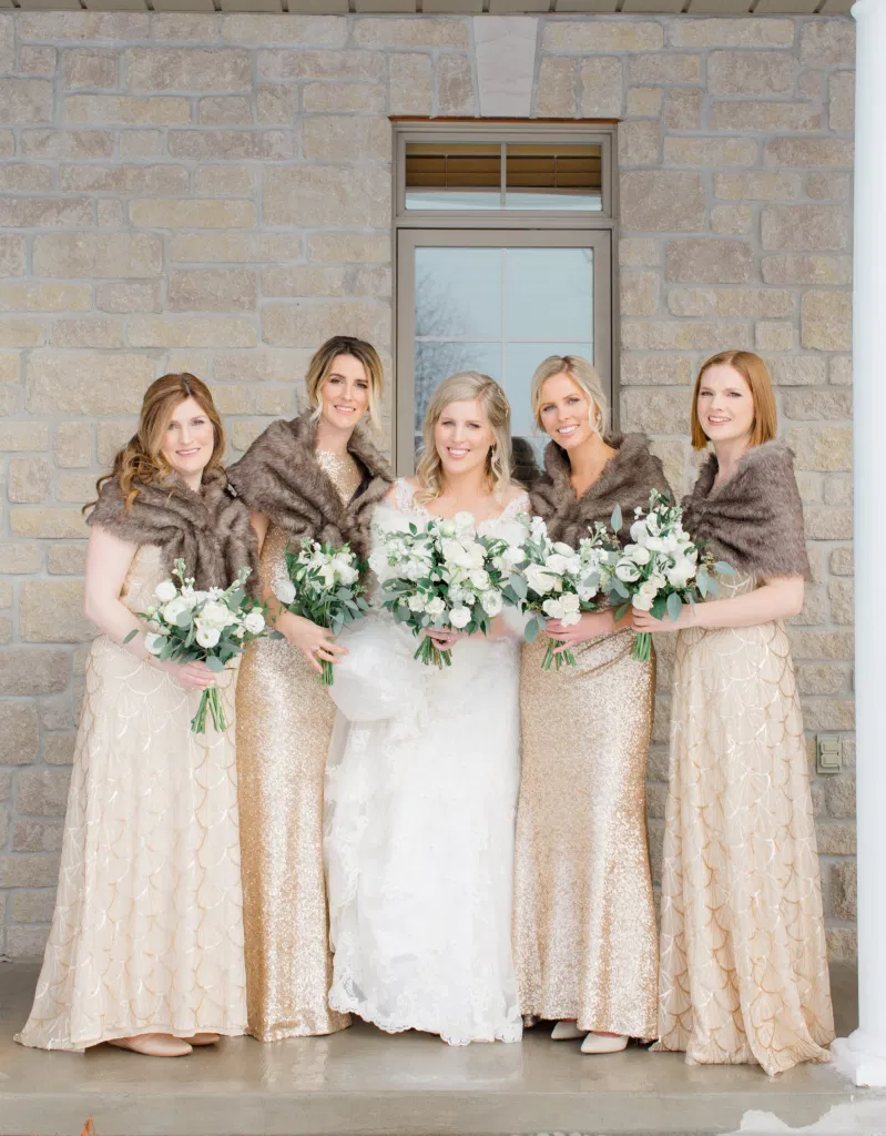 Bride with Bridesmaids about to get into the Limo - White, Greenery, Gold Inspired with brown furs - Winter Wedding - Bride with Bridesmaids - Gold, White, Greenery with Brown Furs -  NYE Wedding - Natural Wedding Posing - Ideas for what to wear for Wedding on NYE Photography, Modern Wedding NYE Wardrobe inspiration- Unsure of what to wear for your wedding, we've got you! Romantic white with greenery theme. Lace Wedding Dress in Ottawa. Grey Loft Studio is Ottawa's Wedding and Engagement Photographer & Videographer for Real couples, showcasing photos that are modern, bright, and fun.  Brookstreet Hotel Kanata 
