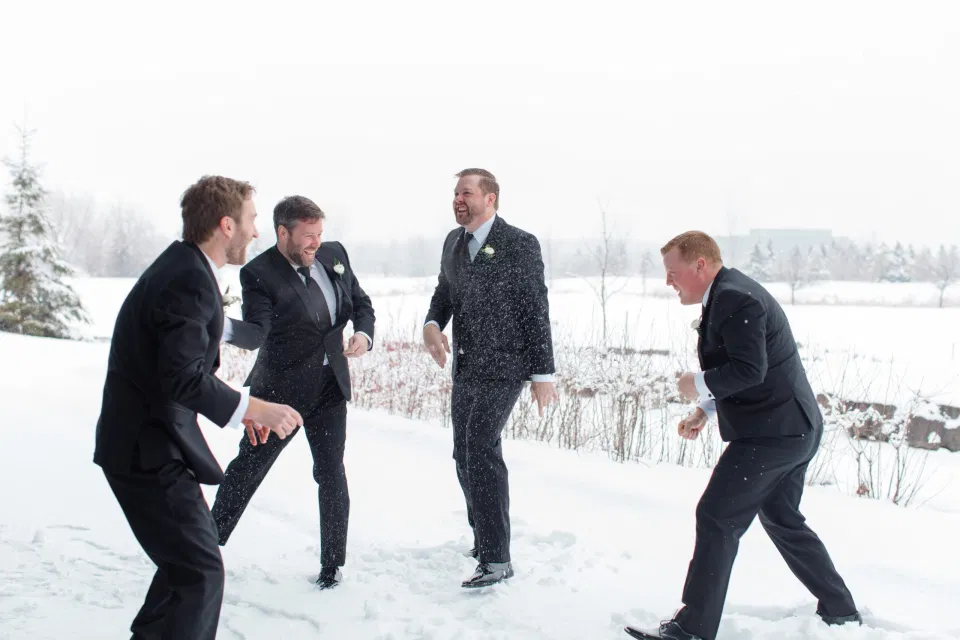 Snowball Fight - Groomsmen - NYE Wedding - Natural Wedding Posing - Ideas for what to wear for Wedding on NYE Photography, Modern Wedding NYE Wardrobe inspiration- Must Have photo at Midnight -  Unsure of what to wear for your wedding, we've got you! Romantic white with greenery theme. Lace Wedding Dress in Ottawa. Grey Loft Studio is Ottawa's Wedding and Engagement Photographer for Real couples, showcasing photos that are modern, bright, and fun.  Brookstreet Hotel Kanata 