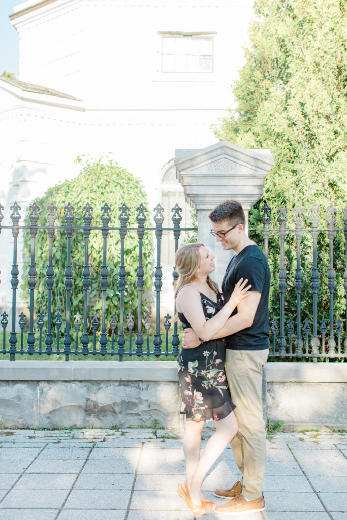 Standing at Rideau Hall - Ideas for what to wear for Engagement Photography, Modern Engagement Session Inspiration Wardrobe Ideas. Unsure of what to wear for your engagement photos, we've got you! Romantic floral dress. Black Polo T-shirt & neutral pants . Boat Shoes and Fancy beaded wedges. Engagement downtown Ottawa. Grey Loft Studio is Ottawa's Wedding and Engagement Photographer Videographer for Real couples, showcasing photos that are modern, bright, and fun.