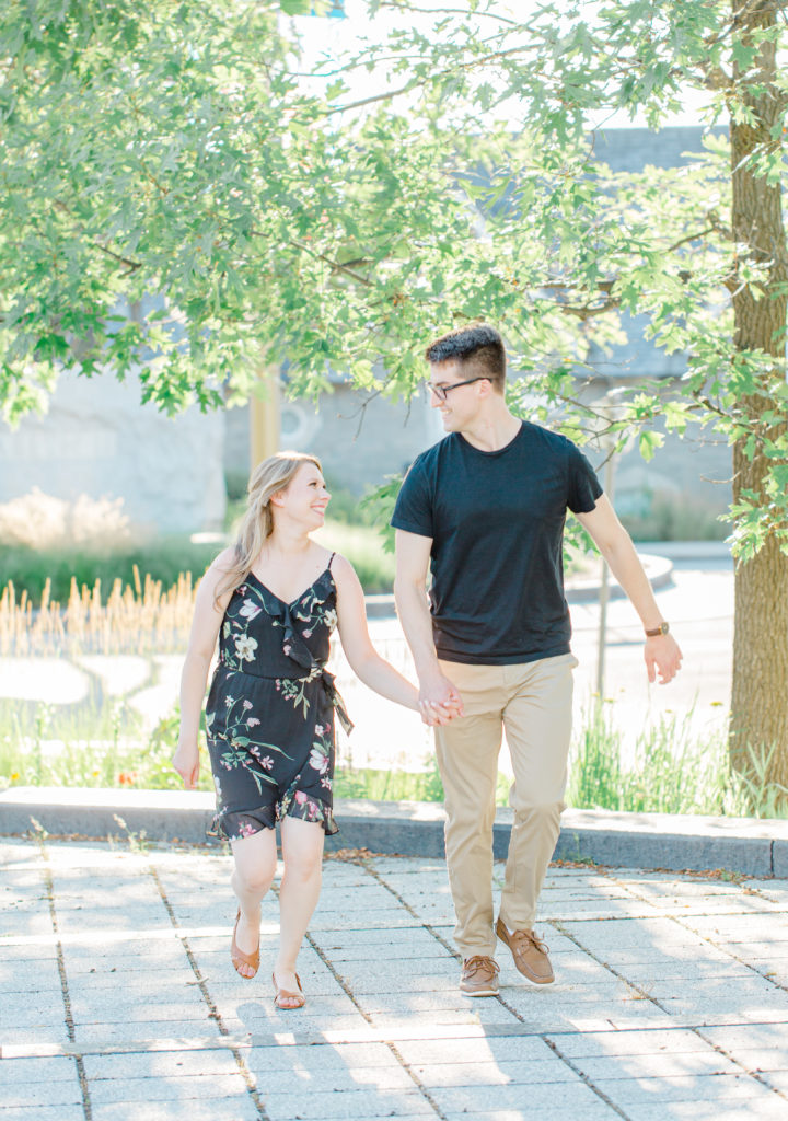 Laughing while posing at Rideau Hall - Ideas for what to wear for Engagement Photography, Modern Engagement Session Inspiration Wardrobe Ideas. Unsure of what to wear for your engagement photos, we've got you! Romantic floral dress. Black Polo T-shirt & neutral pants . Boat Shoes and Fancy beaded wedges. Engagement downtown Ottawa. Grey Loft Studio is Ottawa's Wedding and Engagement Photographer Videographer for Real couples, showcasing photos that are modern, bright, and fun.