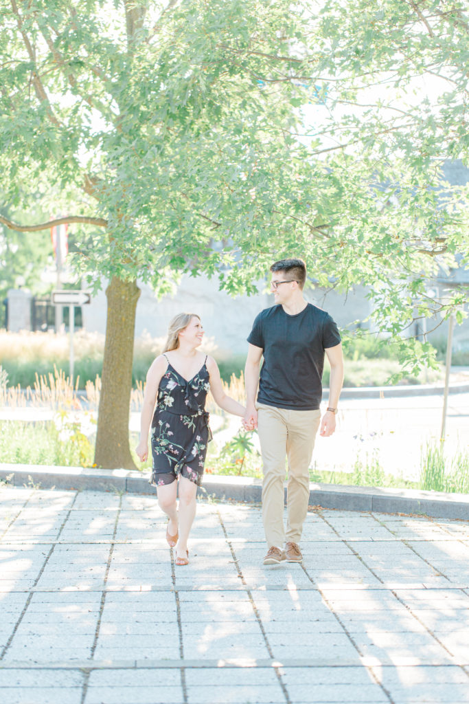 Cute couple Posing at Rideau Hall - Ideas for what to wear for Engagement Photography, Modern Engagement Session Inspiration Wardrobe Ideas. Unsure of what to wear for your engagement photos, we've got you! Romantic floral dress. Black Polo T-shirt & neutral pants . Boat Shoes and Fancy beaded wedges. Engagement downtown Ottawa. Grey Loft Studio is Ottawa's Wedding and Engagement Photographer Videographer for Real couples, showcasing photos that are modern, bright, and fun.