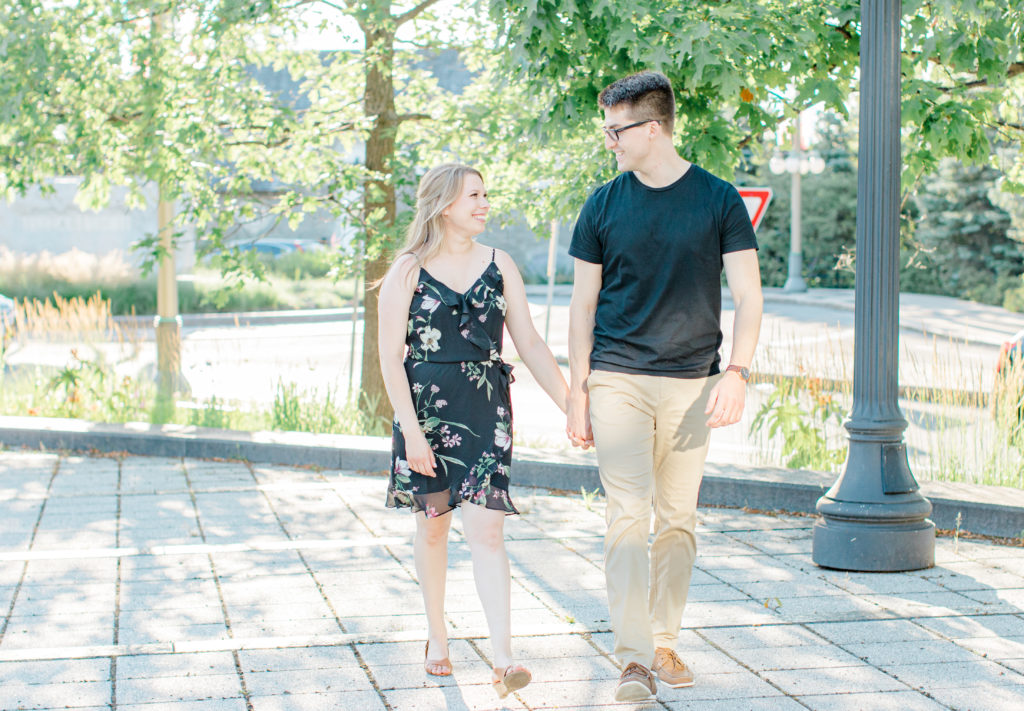 Cute couple Posing at Rideau Hall - Ideas for what to wear for Engagement Photography, Modern Engagement Session Inspiration Wardrobe Ideas. Unsure of what to wear for your engagement photos, we've got you! Romantic floral dress. Black Polo T-shirt & neutral pants . Boat Shoes and Fancy beaded wedges. Engagement downtown Ottawa. Grey Loft Studio is Ottawa's Wedding and Engagement Photographer Videographer for Real couples, showcasing photos that are modern, bright, and fun.