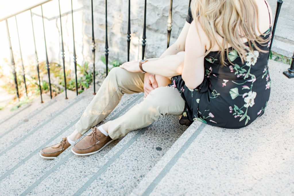 Engagement Photo Poses- Cute couple Posing while sitting on steps at Rideau Hall - Ideas for what to wear for Engagement Photography, Modern Engagement Session Inspiration Wardrobe Ideas. Unsure of what to wear for your engagement photos, we've got you! Romantic floral dress. Black Polo T-shirt & neutral pants . Boat Shoes and Fancy beaded wedges. Engagement downtown Ottawa. Grey Loft Studio is Ottawa's Wedding and Engagement Photographer Videographer for Real couples, showcasing photos that are modern, bright, and fun.