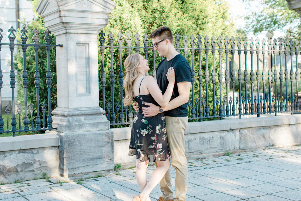 Standing at Rideau Hall - Ideas for what to wear for Engagement Photography, Modern Engagement Session Inspiration Wardrobe Ideas. Unsure of what to wear for your engagement photos, we've got you! Romantic floral dress. Black Polo T-shirt & neutral pants . Boat Shoes and Fancy beaded wedges. Engagement downtown Ottawa. Grey Loft Studio is Ottawa's Wedding and Engagement Photographer Videographer for Real couples, showcasing photos that are modern, bright, and fun.