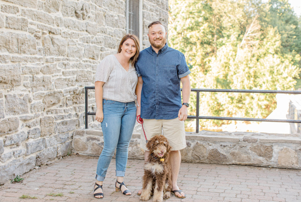 Chocolate Golden Doodle Puppy - grey loft studio -engagement session - Watson's Mill Engagement Session Manotick - Bright & Airy photography - Grey Loft Studio - Ottawa Wedding Photographer - Ottawa Wedding Videographer - Engagement Session Locations in Ottawa - Summer Engagement session - Light blue and Cream with casual jeans and strap sandals. Ottawa Photo Studio.
