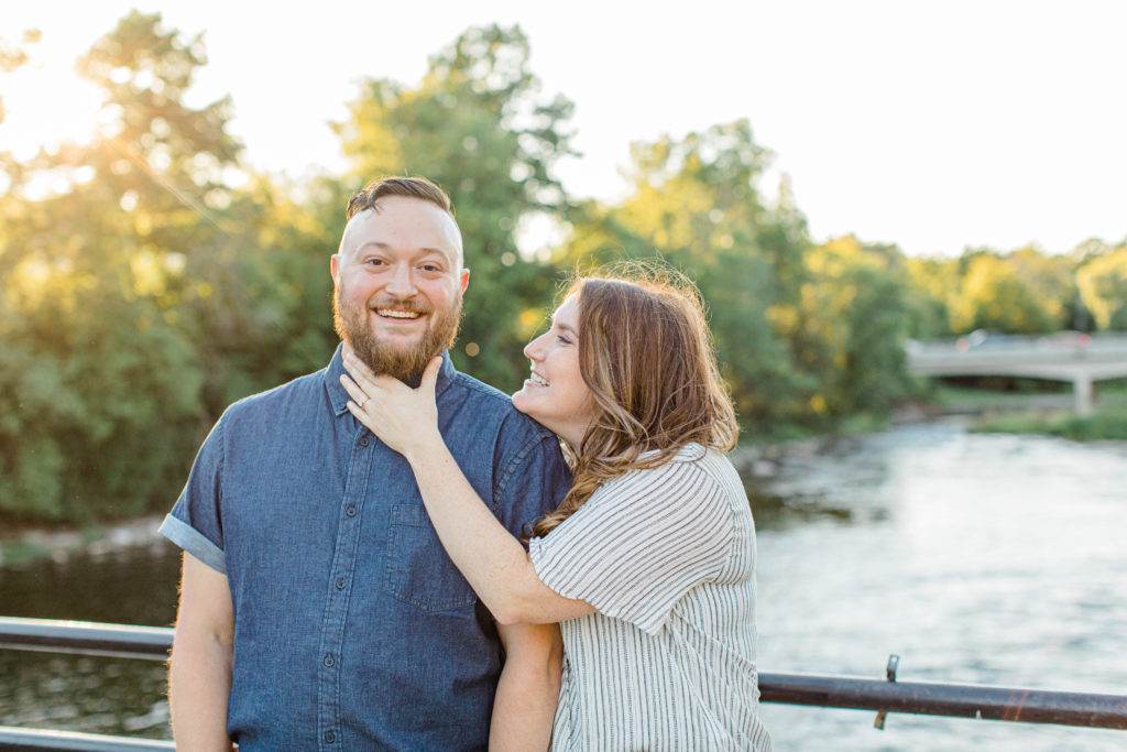 Couple holding each other close -engagement session - Watson's Mill Engagement Session Manotick - Bright & Airy photography - Grey Loft Studio - Ottawa Wedding Photographer - Ottawa Wedding Videographer - Engagement Session Locations in Ottawa - Summer Engagement session - Light blue and Cream with casual jeans and strap sandals. Ottawa Photo Studio.