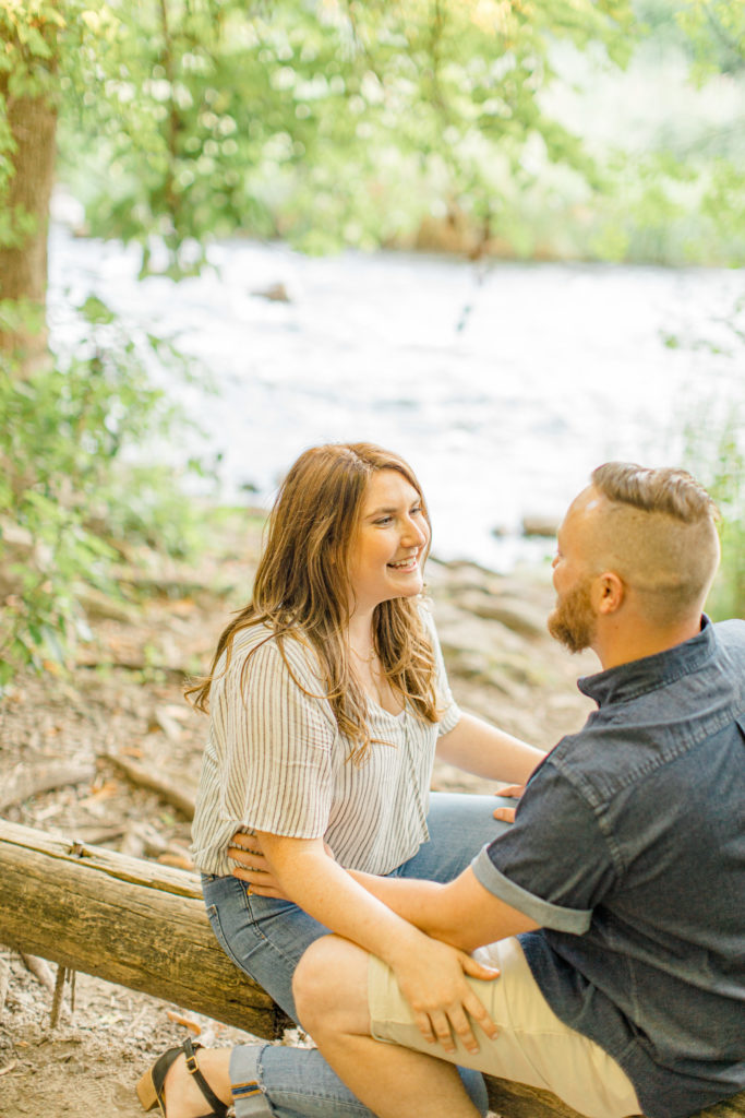 Having fun during engagement session as a couple - sitting on a log