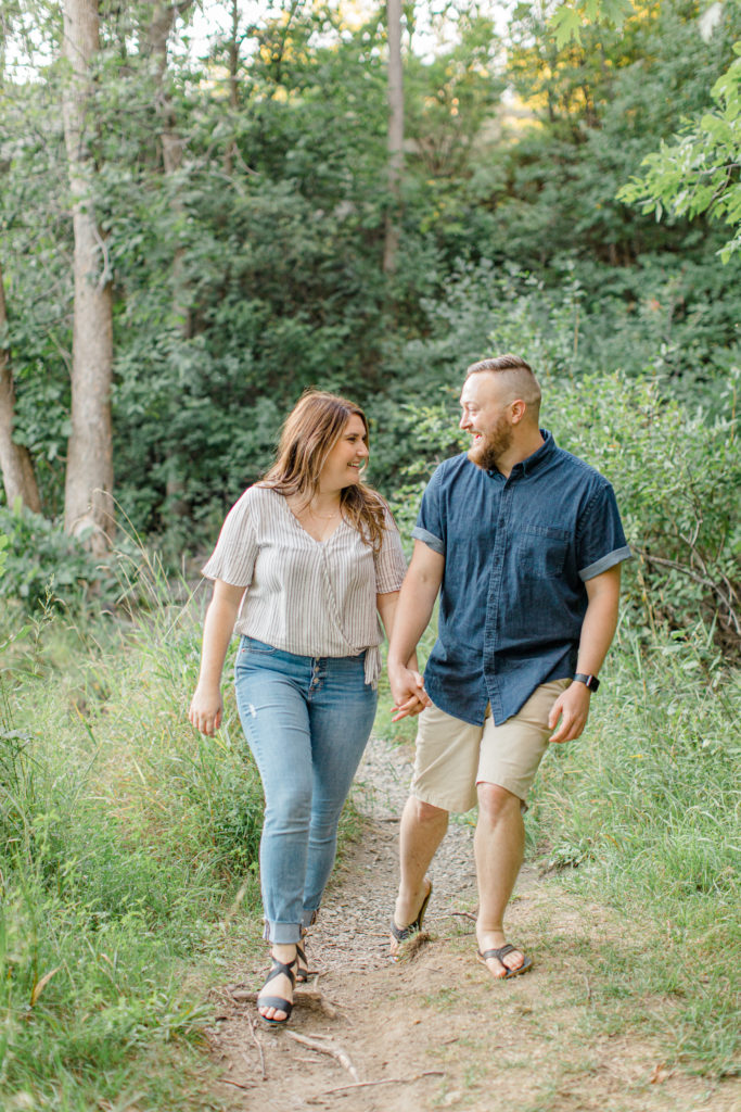 Couple Holding hands during engagement session - Watson's Mill Engagement Session Manotick - Bright & Airy photography - Grey Loft Studio - Ottawa Wedding Photographer - Ottawa Wedding Videographer - Engagement Session Locations in Ottawa - Summer Engagement session - Light blue and Cream with casual jeans and strap sandals. Ottawa Photo Studio.