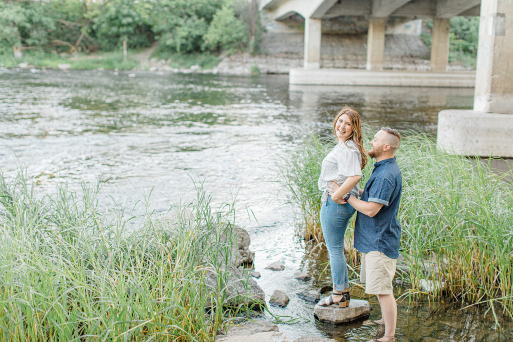 Fun in the water - Watson's Mill Engagement Session Manotick - Bright & Airy photography - Grey Loft Studio - Ottawa Wedding Photographer - Ottawa Wedding Videographer - Engagement Session Locations in Ottawa - Summer Engagement session - Light blue and Cream with casual jeans and strap sandals. Ottawa Photo Studio.