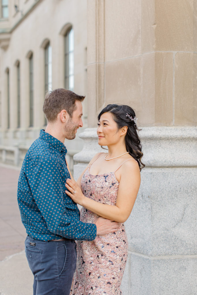 Couple during and Engagement Shoot Downtown Ottawa beside Chateau Laurier - Pink Floral Dress paired seamlessly with Blue Button Up Shirt and Dark Blue Khaki Pants.  Grey Loft Studio - Ottawa Wedding Photographer - Light and Airy photos, husband and wife Team. 