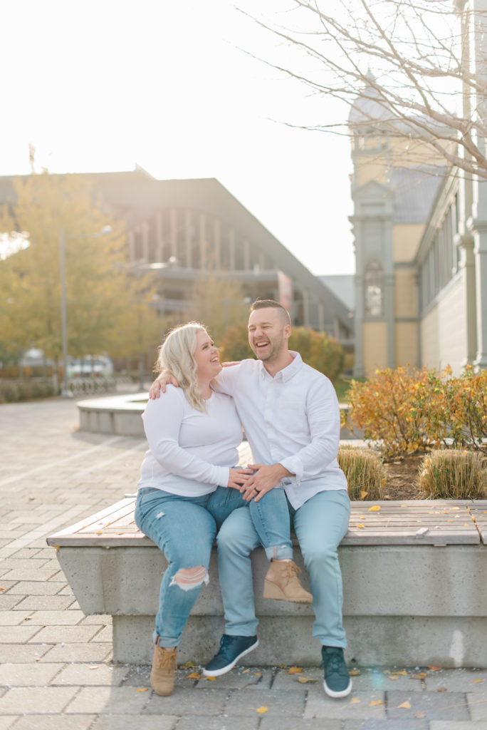 man and woman also husband and wife posing in downtown Ottawa at Lansdowne park wearing white shirts and blue jeans with the sun behind them on a warm November day - Posing ideas - Poses - Couple - Pose with Husband - Pose with Wife - Matching photoshoot - Matching couple